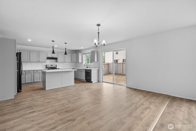 14933 Terra View St SE, Yelm, WA 98597 - kitchen with black appliances, gray cabinetry, a chandelier, under cabinet range hood, and decorative backsplash