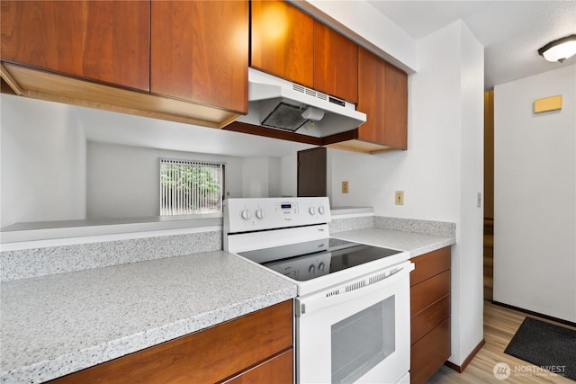 18910 Bothell Everett Hwy Unit K3, Bothell, WA 98012 - kitchen with white electric range oven, under cabinet range hood, brown cabinets, light countertops, and light wood-type flooring