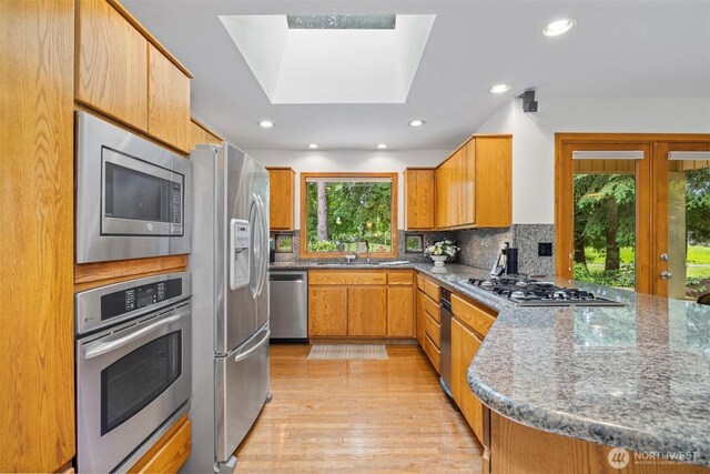 8834 Goldeneye Ln, Blaine, WA 98230 - kitchen featuring appliances with stainless steel finishes, light wood finished floors, recessed lighting, tasteful backsplash, and a skylight