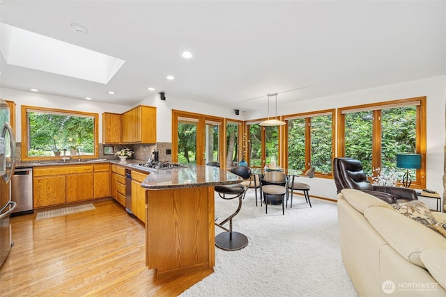 8834 Goldeneye Ln, Blaine, WA 98230 - kitchen with a peninsula, open floor plan, a skylight, a breakfast bar area, and dark stone counters