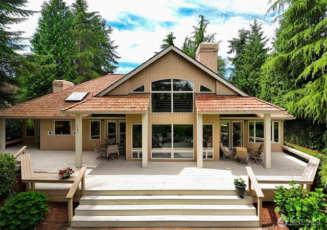 8834 Goldeneye Ln, Blaine, WA 98230 - back of property featuring a chimney, outdoor dining space, and a wooden deck