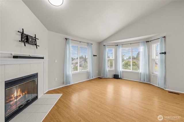 742 N 103rd St, Seattle, WA 98133 - unfurnished living room featuring lofted ceiling, a tile fireplace, light wood-style floors, and healthy amount of natural light