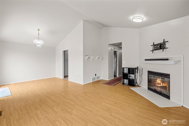 742 N 103rd St, Seattle, WA 98133 - unfurnished living room featuring vaulted ceiling, a fireplace, wood finished floors, and a chandelier