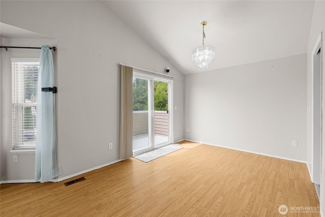 742 N 103rd St, Seattle, WA 98133 - empty room with healthy amount of natural light, vaulted ceiling, light wood-type flooring, and a chandelier
