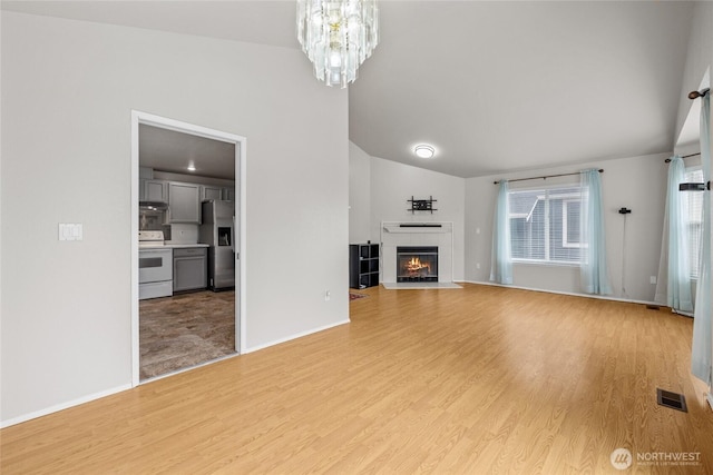 742 N 103rd St, Seattle, WA 98133 - unfurnished living room featuring lofted ceiling, light wood-style floors, a fireplace, and a chandelier