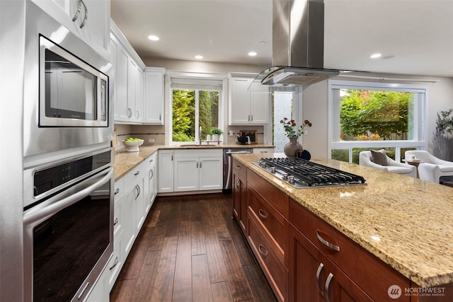 17477 NE 123rd Way, Redmond, WA 98052 - kitchen featuring appliances with stainless steel finishes, island exhaust hood, light stone countertops, dark wood-type flooring, and white cabinetry