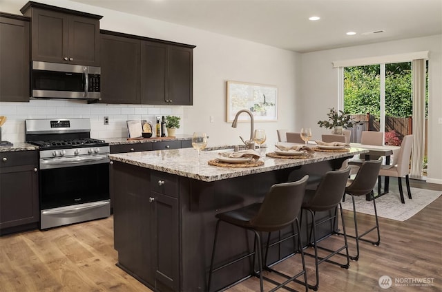 12611 37th Pl NE, Lake Stevens, WA 98258 - kitchen featuring stainless steel appliances, light wood-style floors, light stone counters, a center island with sink, and recessed lighting