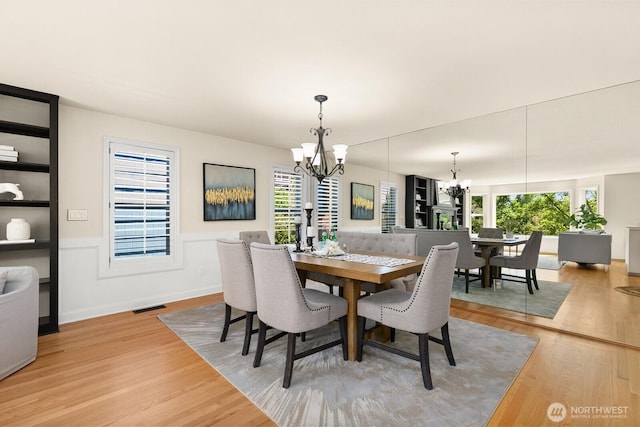 2218 N 38th St, Seattle, WA 98103 - dining room featuring a chandelier, light wood-type flooring, and wainscoting