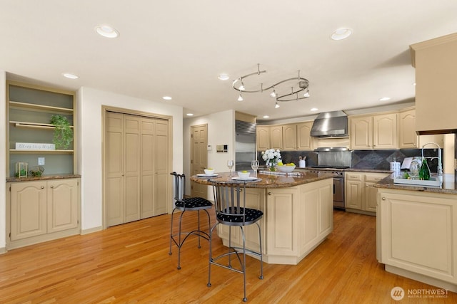2218 N 38th St, Seattle, WA 98103 - kitchen featuring high quality appliances, wall chimney exhaust hood, a kitchen bar, light wood finished floors, and a center island