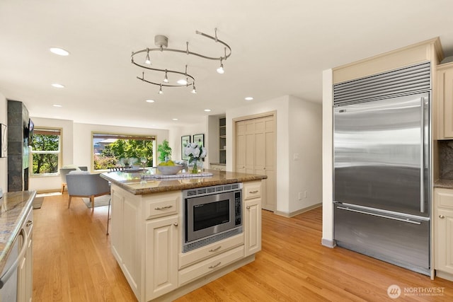 2218 N 38th St, Seattle, WA 98103 - kitchen featuring built in appliances, light wood-style floors, stone counters, recessed lighting, and a center island