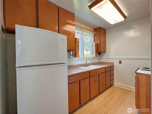 304 Columbia Ave, Coulee Dam, WA 99116 - kitchen featuring freestanding refrigerator, light wood finished floors, brown cabinetry, and light countertops