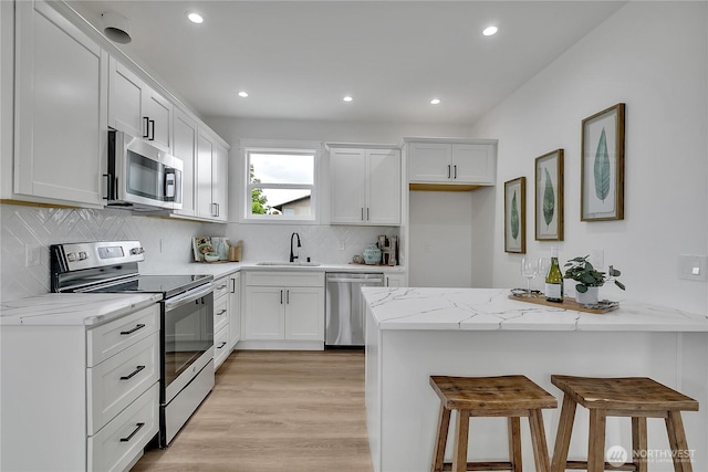 1215 N 10th St, Tacoma, WA 98403 - kitchen with appliances with stainless steel finishes, a peninsula, a breakfast bar area, light wood finished floors, and recessed lighting
