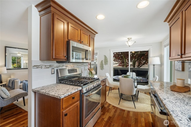 2344 44th Ave SW Unit B, Seattle, WA 98116 - kitchen featuring appliances with stainless steel finishes, dark wood-style floors, brown cabinets, recessed lighting, and tasteful backsplash