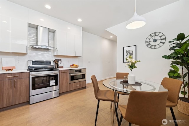 1742 12th Ave S Unit A, Seattle, WA 98144 - kitchen with appliances with stainless steel finishes, wall chimney range hood, white cabinetry, light countertops, and recessed lighting