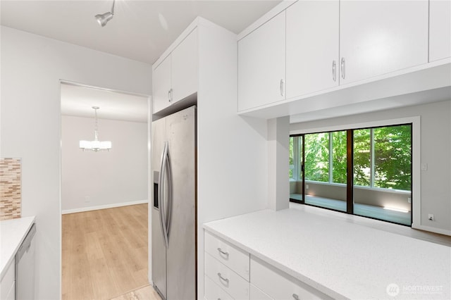 5101 NE 55th St Unit 103, Seattle, WA 98105 - kitchen featuring stainless steel appliances, light countertops, white cabinetry, and light wood-style flooring