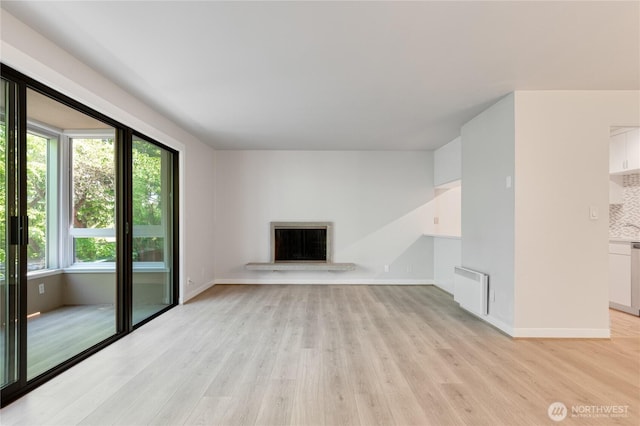 5101 NE 55th St Unit 103, Seattle, WA 98105 - unfurnished living room with light wood-style floors, radiator, and a fireplace with raised hearth