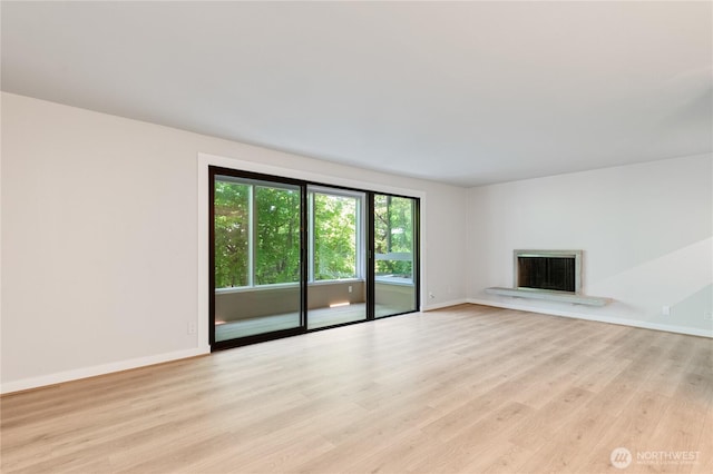 5101 NE 55th St Unit 103, Seattle, WA 98105 - unfurnished living room featuring a fireplace with raised hearth and light wood-style flooring