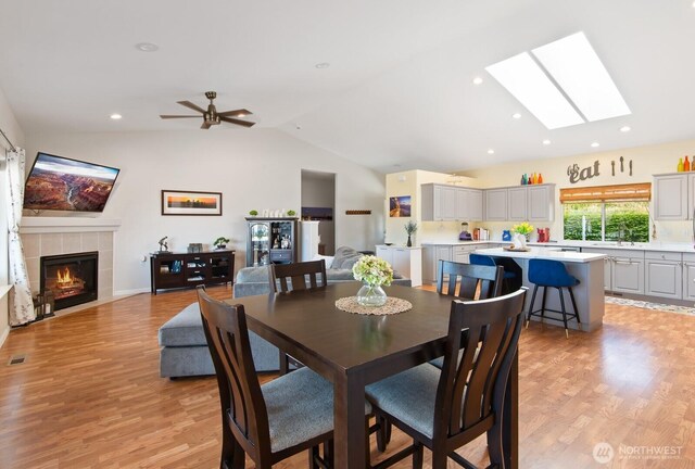 2615 N Baker Ave, East Wenatchee, WA 98802 - dining space featuring vaulted ceiling, a skylight, a tiled fireplace, light wood-type flooring, and recessed lighting