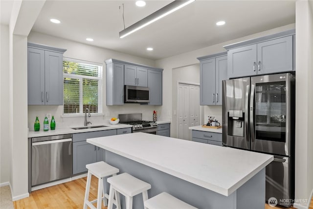 7526 148th Pl SE, Snohomish, WA 98296 - kitchen with stainless steel appliances, gray cabinets, light countertops, a kitchen breakfast bar, and light wood-style flooring