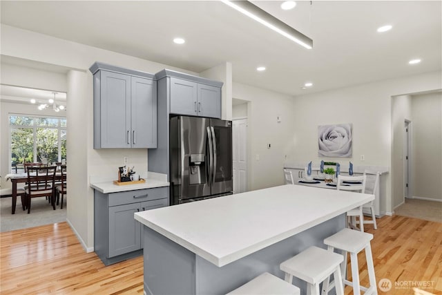 7526 148th Pl SE, Snohomish, WA 98296 - kitchen featuring stainless steel fridge with ice dispenser, gray cabinets, a breakfast bar, light countertops, and light wood-style flooring