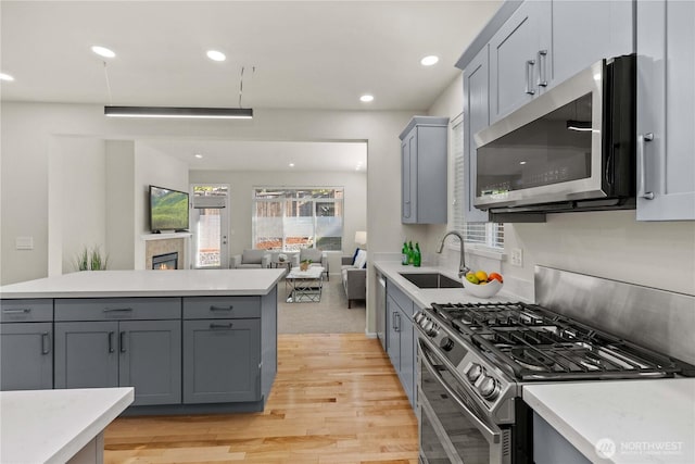 7526 148th Pl SE, Snohomish, WA 98296 - kitchen with stainless steel appliances, gray cabinets, light wood-style flooring, open floor plan, and light countertops