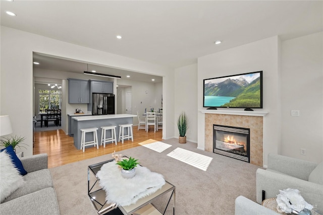 7526 148th Pl SE, Snohomish, WA 98296 - living room with recessed lighting, a tiled fireplace, light wood-style floors, and light colored carpet