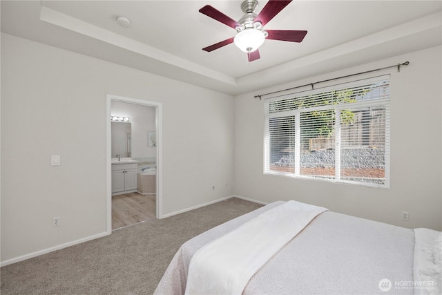 7526 148th Pl SE, Snohomish, WA 98296 - bedroom with light colored carpet, a tray ceiling, connected bathroom, and a ceiling fan