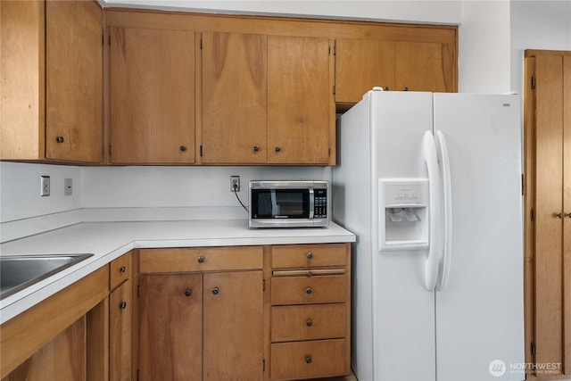 22223 10th Ave S, Des Moines, WA 98198 - kitchen featuring white fridge with ice dispenser, stainless steel microwave, light countertops, and brown cabinets