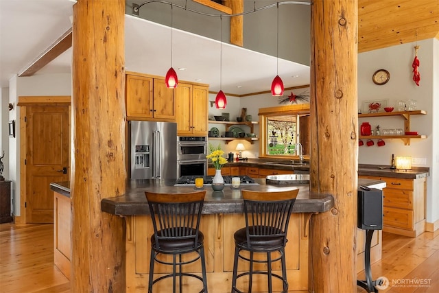 639 A Twisp River Rd, Twisp, WA 98856 - kitchen featuring stainless steel appliances, open shelves, dark countertops, light wood-style floors, and a kitchen bar