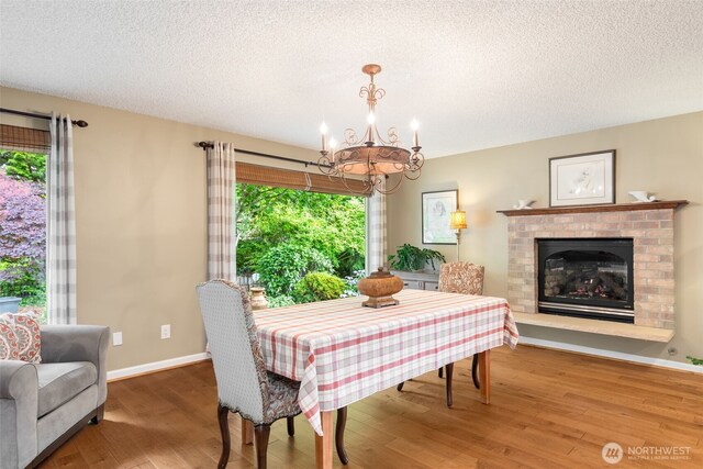 24812 12th Ave S, Des Moines, WA 98198 - dining space with a chandelier, wood finished floors, a textured ceiling, and a fireplace