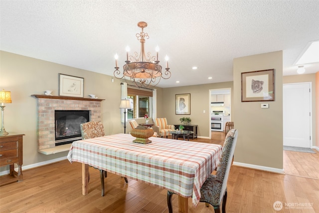 24812 12th Ave S, Des Moines, WA 98198 - dining area featuring a chandelier, light wood finished floors, a fireplace, recessed lighting, and a textured ceiling