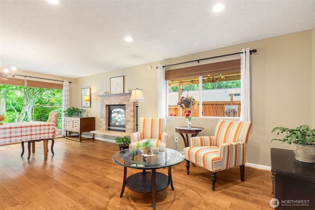 24812 12th Ave S, Des Moines, WA 98198 - living room featuring healthy amount of natural light, recessed lighting, light wood-style flooring, a textured ceiling, and a glass covered fireplace