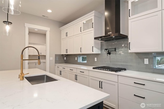 7560 S 130th Pl, Seattle, WA 98178 - kitchen featuring wall chimney range hood, stainless steel gas stovetop, white cabinetry, backsplash, and glass insert cabinets