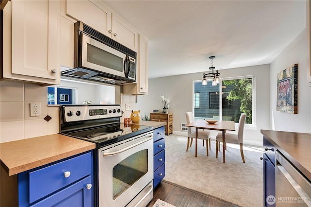 8021 234th St SW Unit 211, Edmonds, WA 98026 - kitchen with stainless steel appliances, blue cabinets, a chandelier, and backsplash