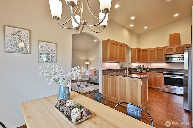 4880 Harbor Hills Dr, Freeland, WA 98249 - kitchen featuring stainless steel appliances, arched walkways, a chandelier, high vaulted ceiling, and dark wood-style floors