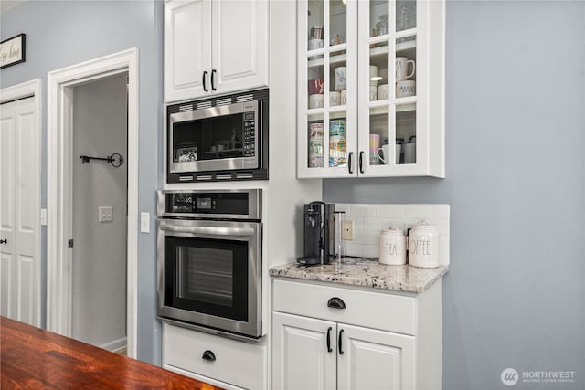 5625 Elizabeth Ave SE, Auburn, WA 98092 - kitchen with appliances with stainless steel finishes, glass insert cabinets, white cabinets, tasteful backsplash, and light stone countertops