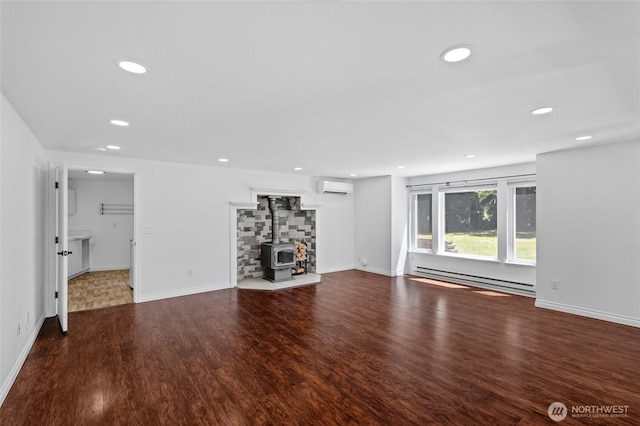 6426 Zangle Rd NE, Olympia, WA 98506 - unfurnished living room featuring a baseboard heating unit, a wall mounted air conditioner, a wood stove, wood finished floors, and recessed lighting