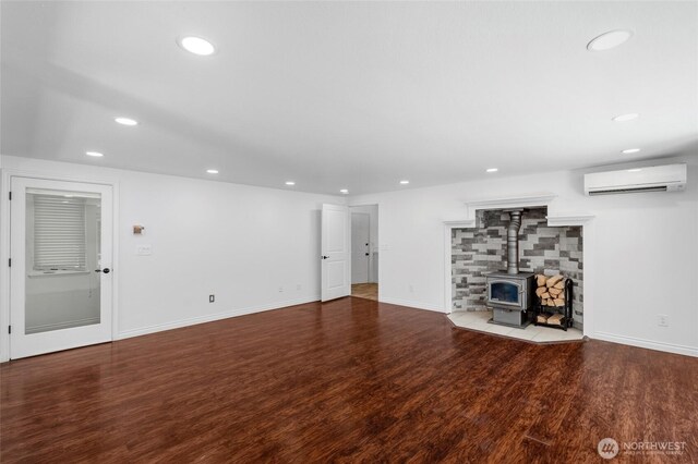 6426 Zangle Rd NE, Olympia, WA 98506 - unfurnished living room featuring a wall unit AC, a wood stove, recessed lighting, and wood finished floors