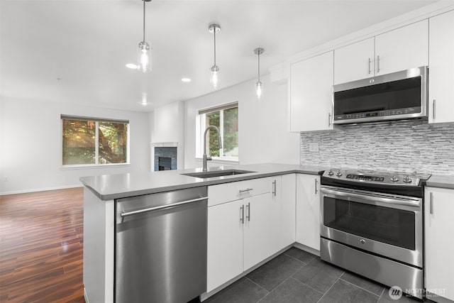 232 Belmont Ave E # 201, Seattle, WA 98102 - kitchen featuring stainless steel appliances, a peninsula, a fireplace, white cabinets, and open floor plan