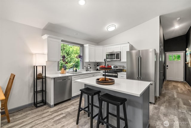 5843 Octave Ct SE, Olympia, WA 98513 - kitchen featuring appliances with stainless steel finishes, vaulted ceiling, white cabinets, light wood-style flooring, and light countertops