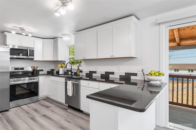 2112 S Crestmont Dr, Moses Lake, WA 98837 - kitchen featuring appliances with stainless steel finishes, a peninsula, light wood finished floors, dark countertops, and white cabinetry