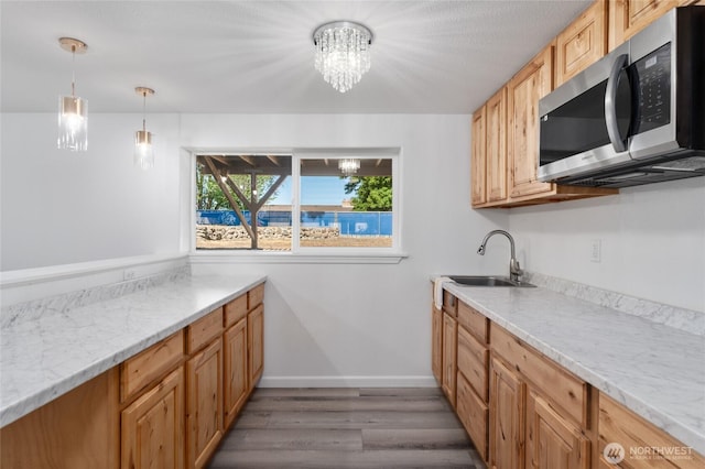 2112 S Crestmont Dr, Moses Lake, WA 98837 - kitchen with stainless steel microwave, a chandelier, wood finished floors, decorative light fixtures, and light stone countertops
