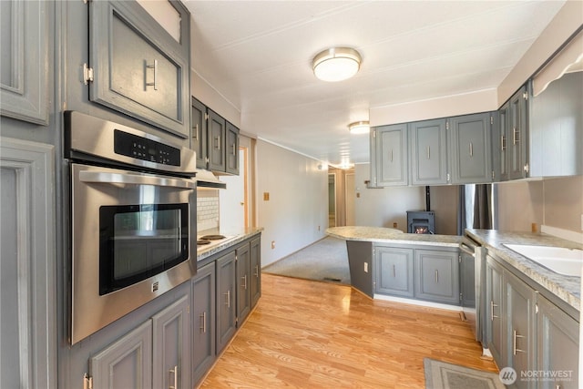 7138 Englewood Dr SE Unit 32, Olympia, WA 98513 - kitchen with appliances with stainless steel finishes, a peninsula, light countertops, light wood-style flooring, and gray cabinetry