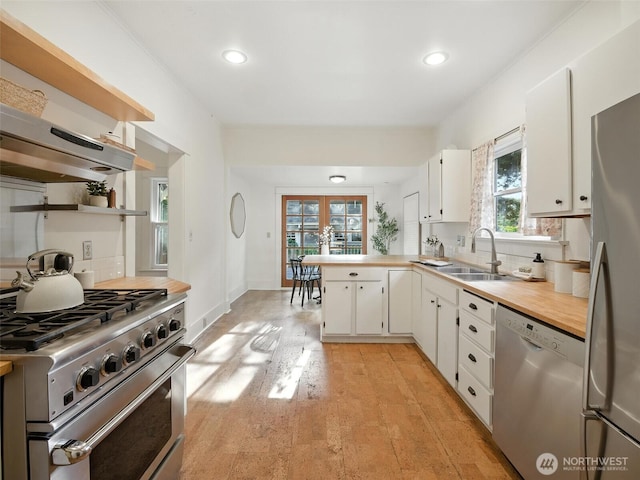 2555 Queen Anne Ave N, Seattle, WA 98109 - kitchen with stainless steel appliances, backsplash, recessed lighting, white cabinetry, and a peninsula