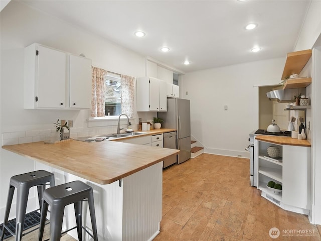 2555 Queen Anne Ave N, Seattle, WA 98109 - kitchen featuring open shelves, stainless steel appliances, a peninsula, a kitchen bar, and recessed lighting