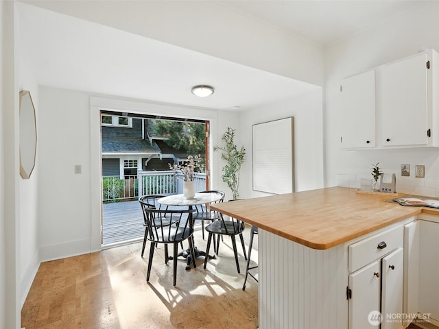 2555 Queen Anne Ave N, Seattle, WA 98109 - kitchen with white cabinetry, light wood-style floors, wooden counters, a peninsula, and a breakfast bar