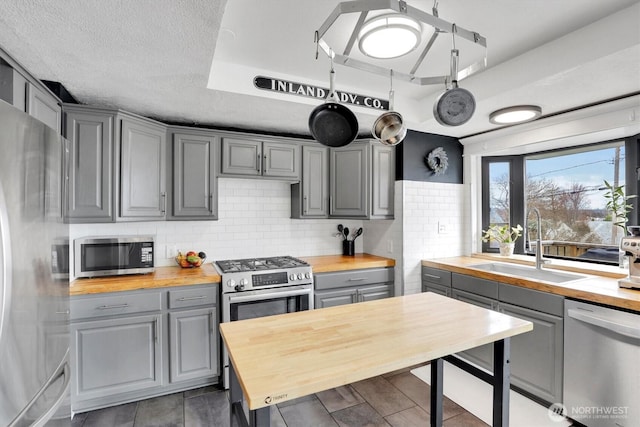 2819 W Olympic Ave, Spokane, WA 99205 - kitchen with butcher block counters, gray cabinets, stainless steel appliances, a tray ceiling, and decorative backsplash