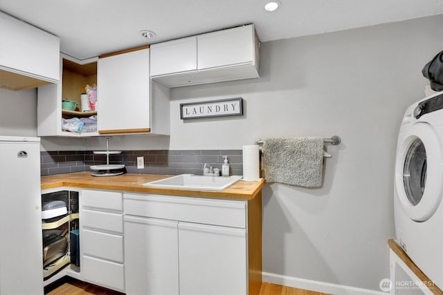 2819 W Olympic Ave, Spokane, WA 99205 - kitchen featuring butcher block countertops, washer / dryer, white cabinetry, and tasteful backsplash