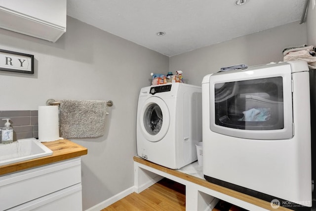 2819 W Olympic Ave, Spokane, WA 99205 - laundry room featuring light wood-type flooring, separate washer and dryer, and cabinet space