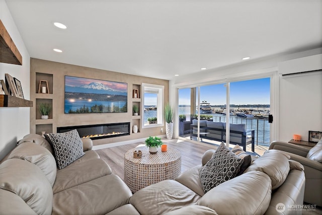 65 Kirkland Ave Unit 108, Kirkland, WA 98033 - living room featuring a wall mounted air conditioner, wood finished floors, a glass covered fireplace, recessed lighting, and built in shelves